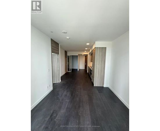 A long hallway with dark wood floors and white walls.