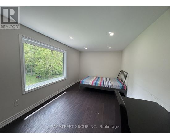 A bedroom with a bed and a window overlooking a green area.