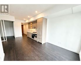 A spacious room with a kitchenette and wooden flooring.