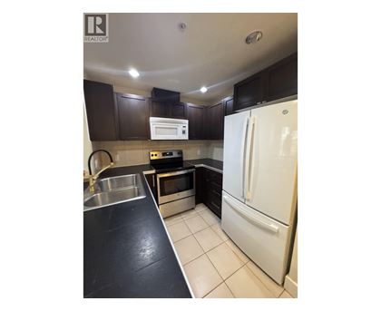 A kitchen with a white fridge and black countertops.