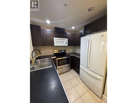 A kitchen with a white fridge and black countertops.