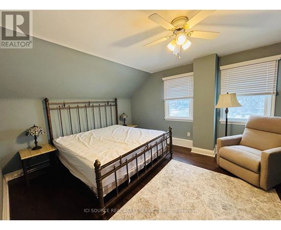 A bedroom with a bed, chair, and ceiling fan.