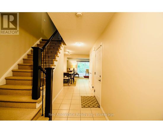 A hallway with a staircase and a dining area in the background.