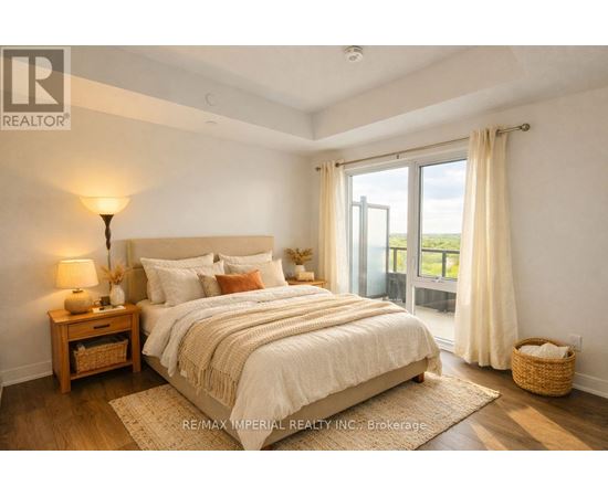 A bedroom with a large bed, a nightstand with a lamp, and a view of the outdoors through a sliding glass door.