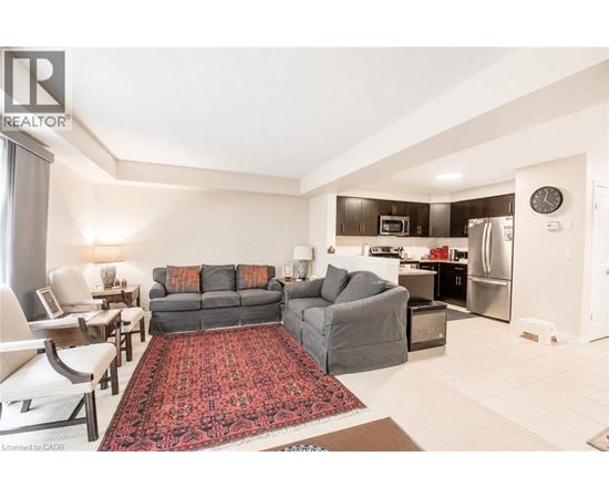A living room with a grey couch and a red rug.