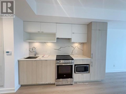 A modern kitchen with a sink, oven, and microwave.