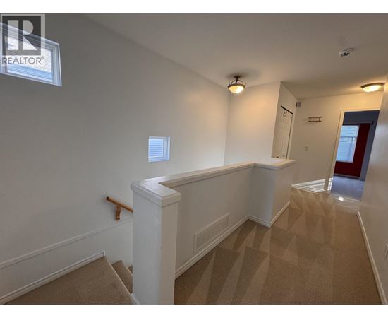 A room with a carpeted floor and a window with blinds.