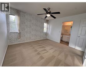 A room with a fan and a brick wall.