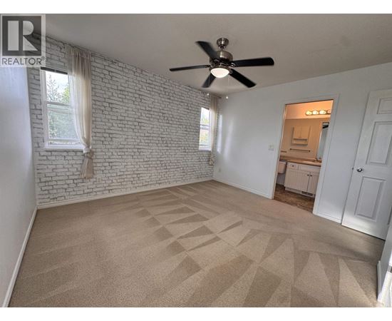 A room with a fan and a brick wall.