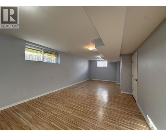 A room with wooden flooring and a window with blinds.