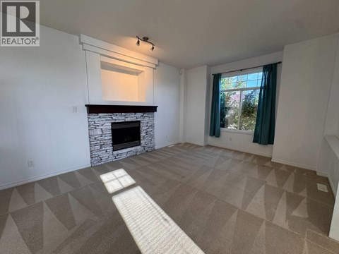 A living room with a fireplace and a carpet with triangular patterns.