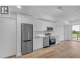 A modern kitchen with a refrigerator, microwave, and oven.