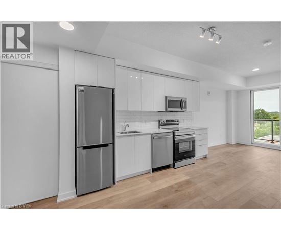 A modern kitchen with a refrigerator, microwave, and oven.