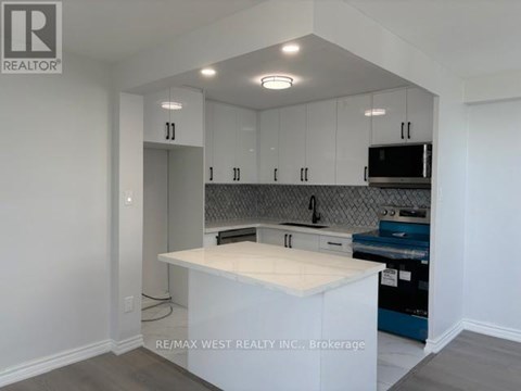 A kitchen with white cabinets and a white island.