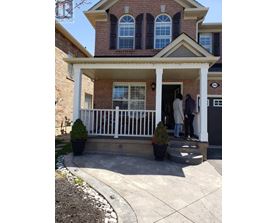 A house with a white porch and two people standing on it.