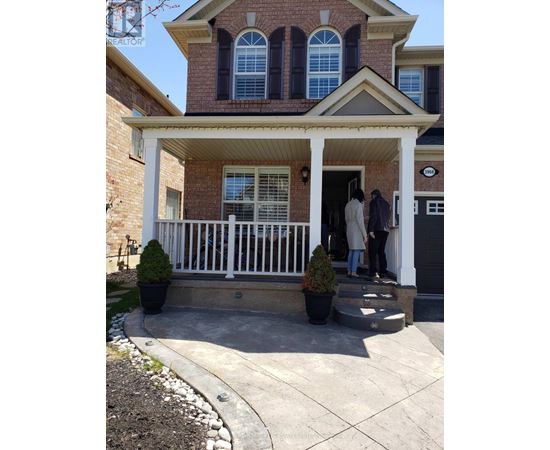 A house with a white porch and two people standing on it.