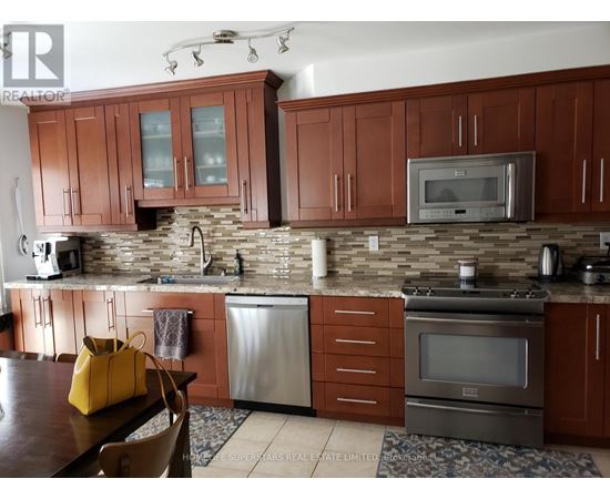 A kitchen with brown cabinets and a stone backsplash.
