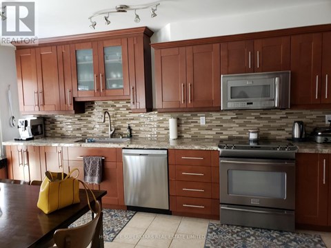 A kitchen with brown cabinets and a stone backsplash.