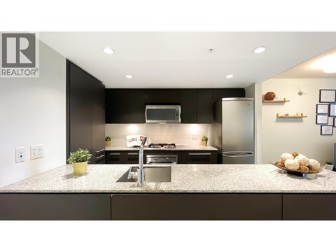 A modern kitchen with a granite countertop and stainless steel appliances.