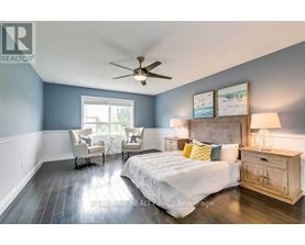 A bedroom with a bed, two chairs, and a ceiling fan.