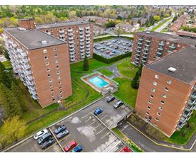An aerial view of a parking lot between two apartment buildings with cars parked in the lot.