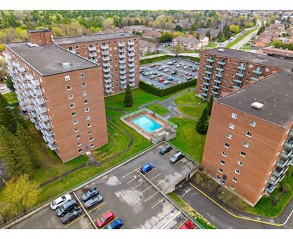 An aerial view of a parking lot between two apartment buildings with cars parked in the lot.