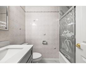A bathroom with a white sink, toilet, and shower area.