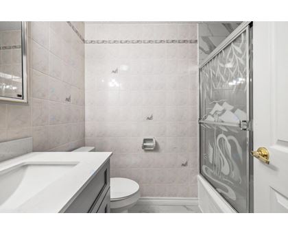A bathroom with a white sink, toilet, and shower area.