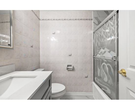 A bathroom with a white sink, toilet, and shower area.