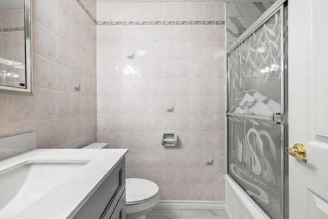 A bathroom with a white sink, toilet, and shower area.