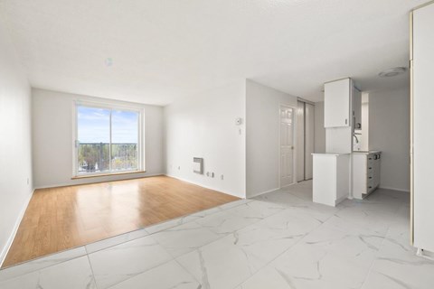 A large empty room with a kitchen area to the right.