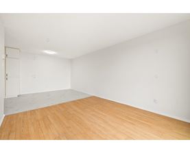 A room with wooden flooring and a white wall.