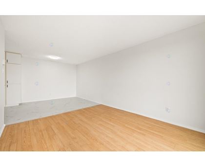 A room with wooden flooring and a white wall.