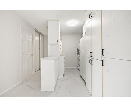 A kitchen with white cabinets and a marble floor.