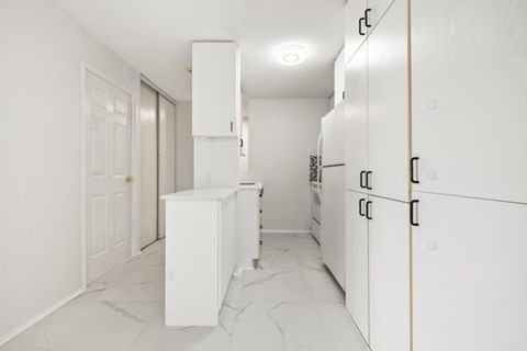 A kitchen with white cabinets and a marble floor.