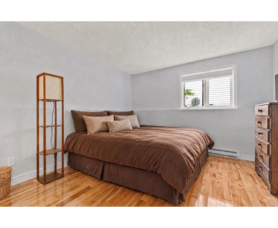 A bedroom with a brown bed and wooden floors.