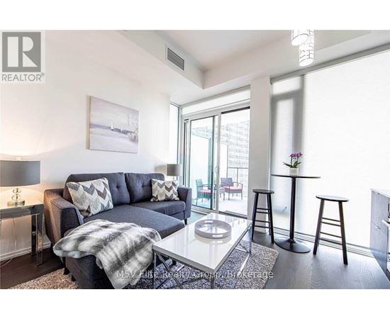 A living room with a grey couch, a coffee table, and a painting on the wall.