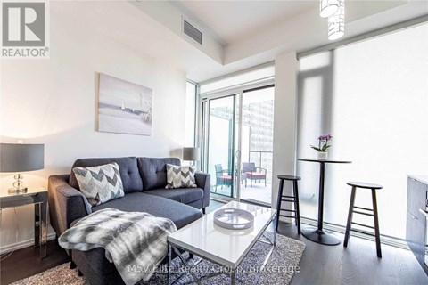 A living room with a grey couch, a coffee table, and a painting on the wall.