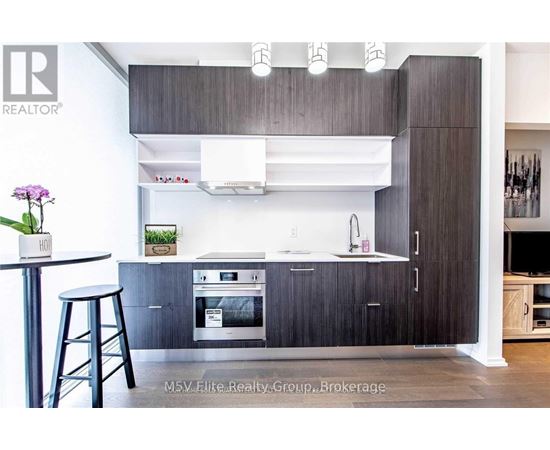 A modern kitchen with dark wood cabinets and stainless steel appliances.
