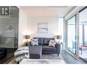 A grey couch with a grey and white blanket on it in a room with a glass door.