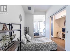 A bedroom with a bed, a shelf, and a window.