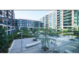 A courtyard with a tree and a bench in front of apartment buildings.