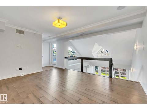 A spacious room with wooden flooring and a large window.