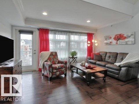 A living room with a grey sofa, a red and white patterned armchair, a wooden coffee table, and a television.
