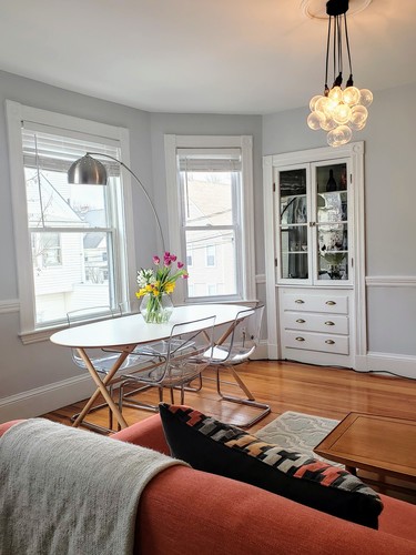 A living room with a white table and chairs, a grey blanket, and a chandelier.