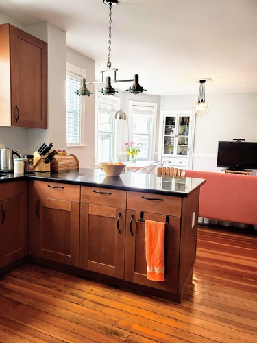 Brown wooden kitchen with a black counter top.