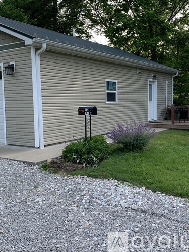 A small house with a gravel driveway in front.