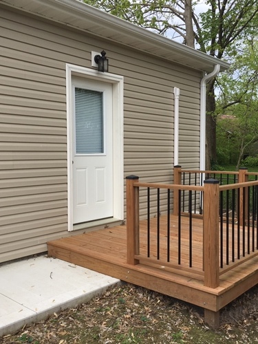 A small house with a white door and a wooden deck.