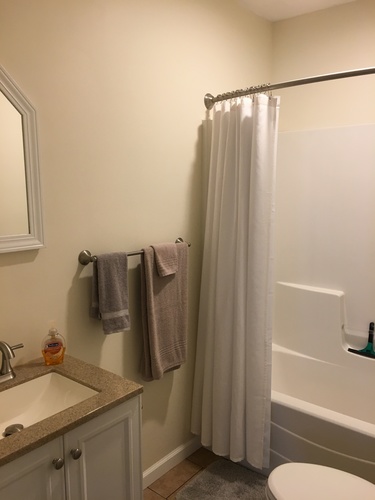 A bathroom with a white shower curtain and a towel hanging on a rack.
