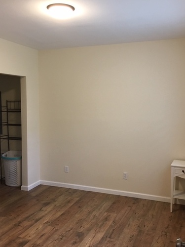 A room with a white wall and wooden flooring.